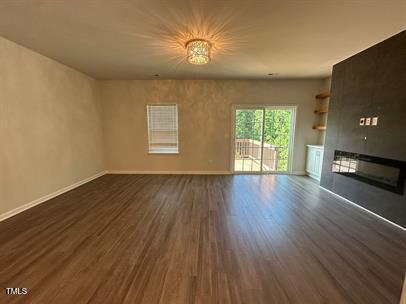 unfurnished living room featuring dark wood-type flooring and a large fireplace