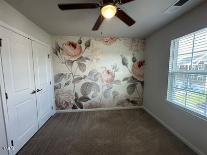 unfurnished bedroom with a closet, ceiling fan, and dark carpet