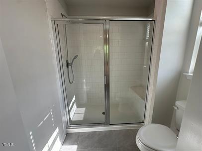 bathroom featuring walk in shower, tile patterned floors, and toilet