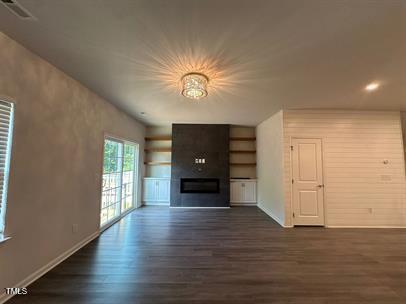 unfurnished living room featuring dark wood-type flooring and a fireplace