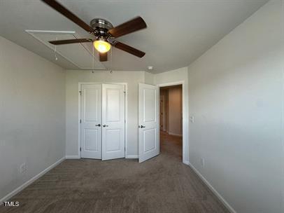 unfurnished bedroom with dark colored carpet and ceiling fan