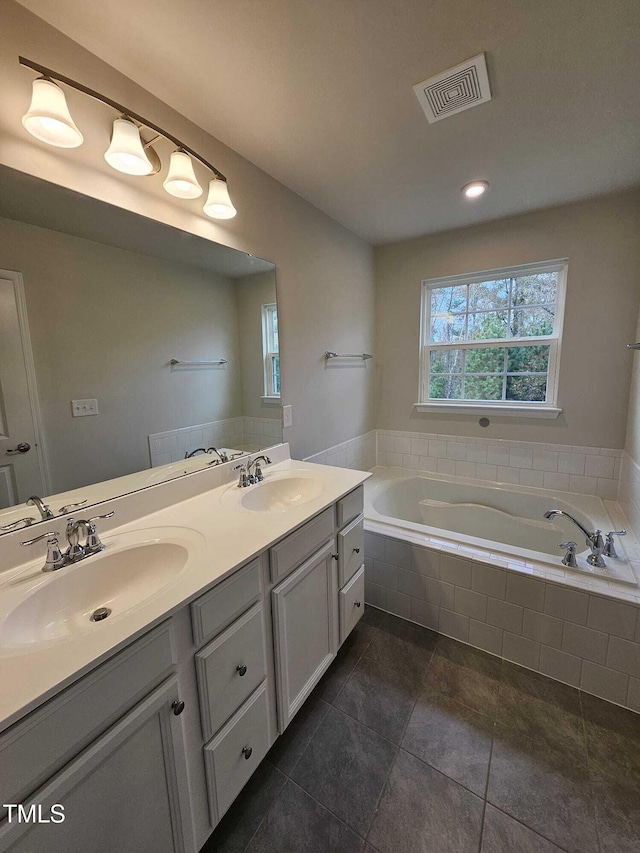 bathroom with a relaxing tiled tub, tile patterned flooring, and vanity