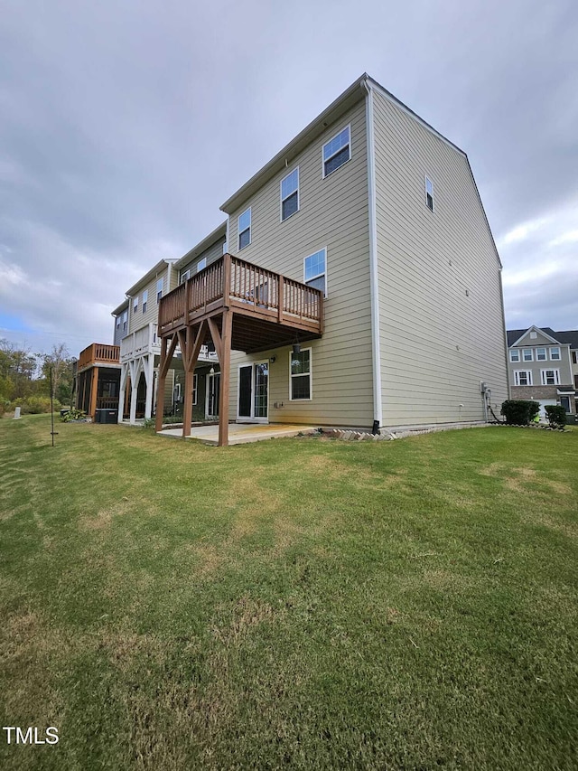 rear view of house featuring a lawn, a wooden deck, and a patio