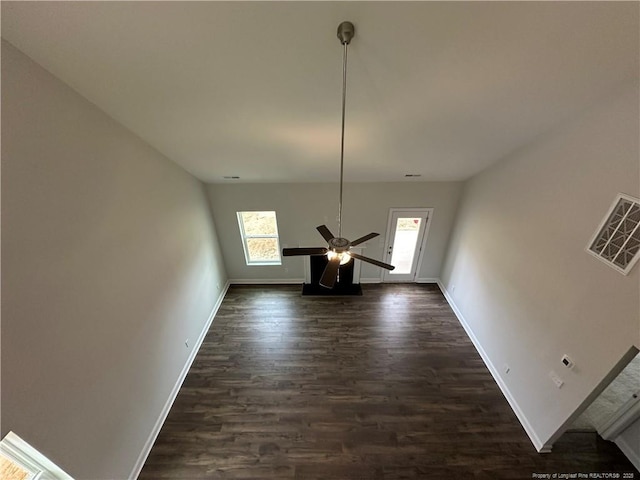 interior space with baseboards, dark wood-style flooring, visible vents, and a healthy amount of sunlight