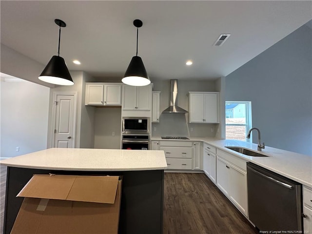 kitchen featuring a sink, white cabinets, light countertops, appliances with stainless steel finishes, and wall chimney exhaust hood