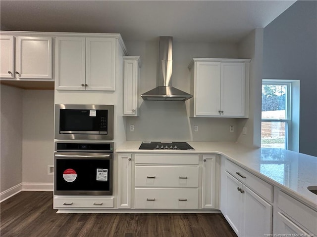 kitchen with wall chimney range hood, white cabinetry, appliances with stainless steel finishes, and dark wood-style flooring