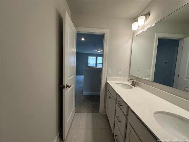 bathroom with double vanity, tile patterned flooring, a sink, and baseboards