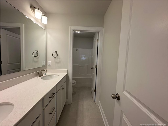 bathroom with double vanity, a sink, toilet, and tile patterned floors