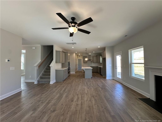 unfurnished living room featuring baseboards, stairs, visible vents, and dark wood finished floors