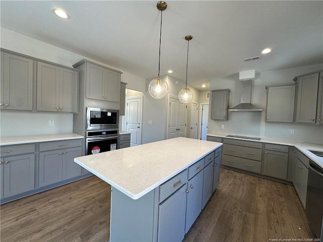 kitchen featuring a center island, gray cabinets, light countertops, appliances with stainless steel finishes, and wall chimney exhaust hood