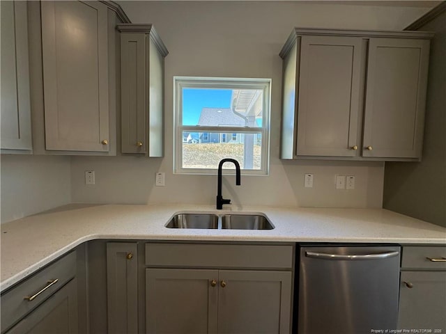 kitchen with stainless steel dishwasher, gray cabinets, a sink, and light stone counters