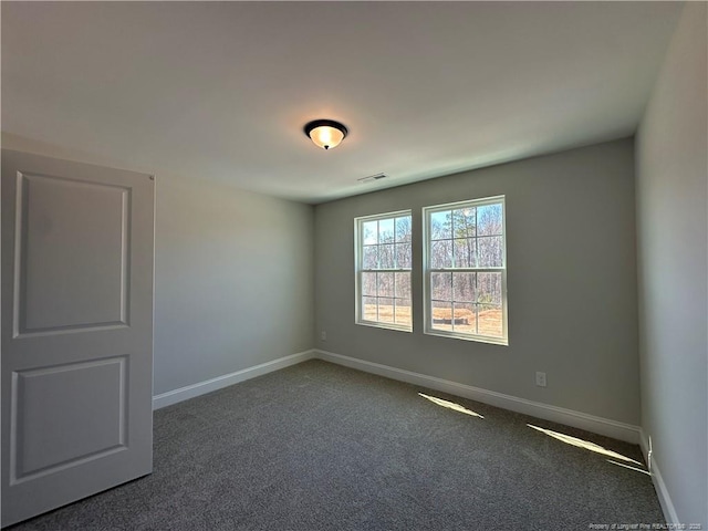 empty room featuring visible vents, baseboards, and dark carpet