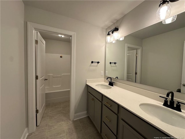 full bathroom with double vanity, baseboards, and a sink