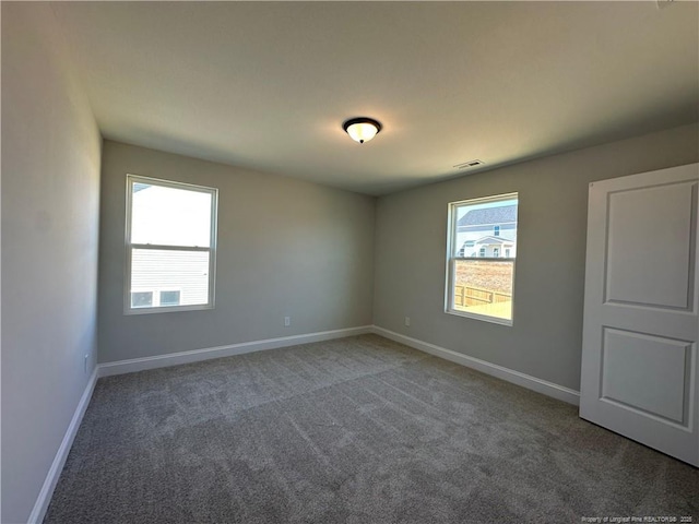 spare room featuring carpet, visible vents, and baseboards