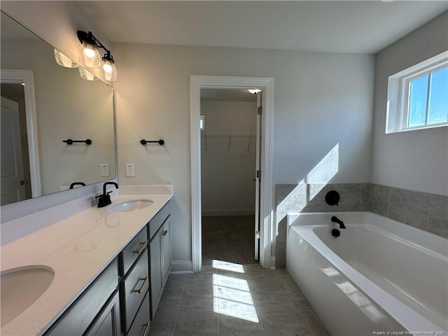 full bathroom with double vanity, a garden tub, a spacious closet, and a sink