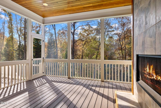 unfurnished sunroom featuring wooden ceiling, a fireplace, and a healthy amount of sunlight