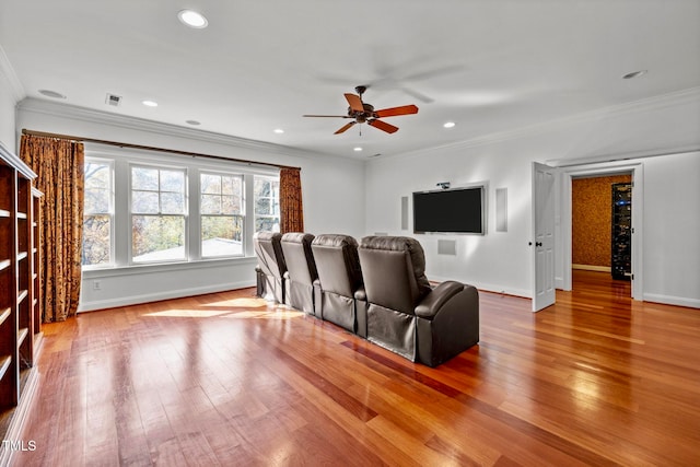 home theater room with ceiling fan, wood-type flooring, and crown molding