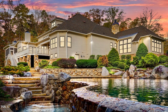 back house at dusk with a small pond