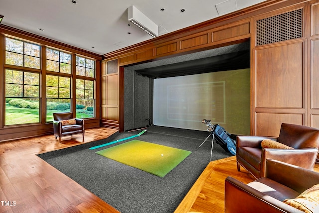 game room featuring golf simulator, hardwood / wood-style flooring, and ornamental molding