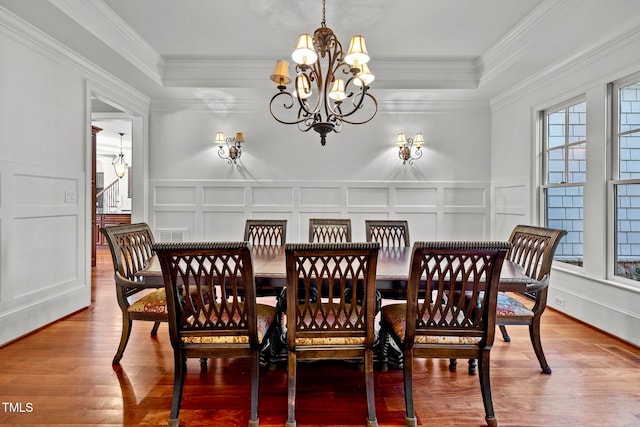 dining area with wood-type flooring, an inviting chandelier, and crown molding