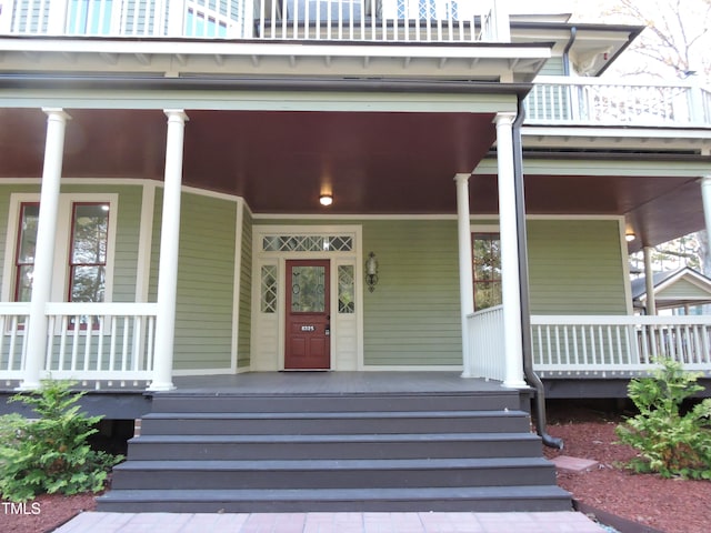 entrance to property with covered porch and a balcony