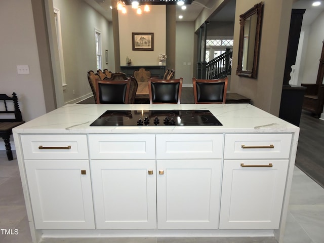 kitchen with light stone countertops, black electric cooktop, and white cabinets