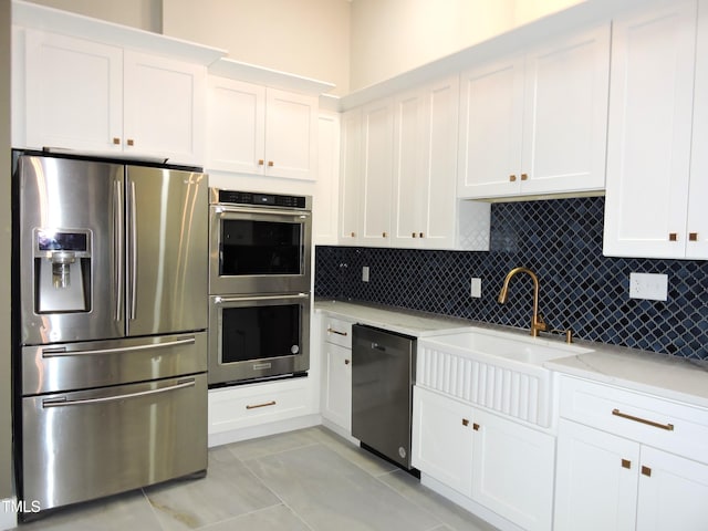 kitchen featuring light tile patterned flooring, appliances with stainless steel finishes, light stone countertops, sink, and white cabinets