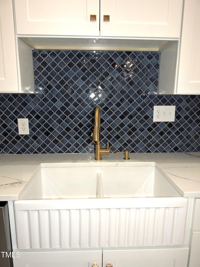 kitchen with backsplash, sink, light stone countertops, and white cabinets