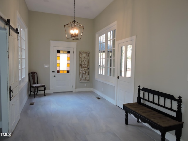 foyer with an inviting chandelier, a barn door, and a healthy amount of sunlight