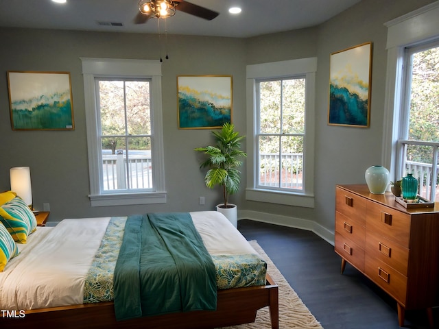 bedroom with dark wood-type flooring, multiple windows, and ceiling fan