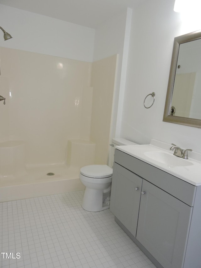 bathroom with toilet, a shower, vanity, and tile patterned floors