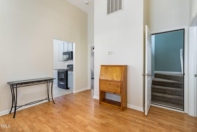 hall featuring high vaulted ceiling and light hardwood / wood-style flooring