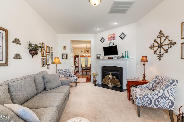 living area featuring a fireplace with flush hearth, a notable chandelier, visible vents, and carpet floors