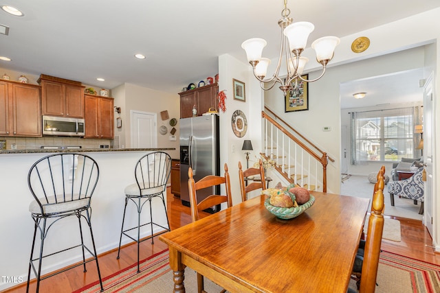 dining space featuring light wood finished floors, visible vents, stairs, recessed lighting, and a notable chandelier