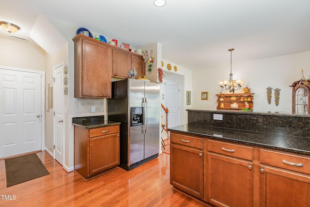 kitchen with light wood finished floors, tasteful backsplash, a chandelier, pendant lighting, and stainless steel refrigerator with ice dispenser