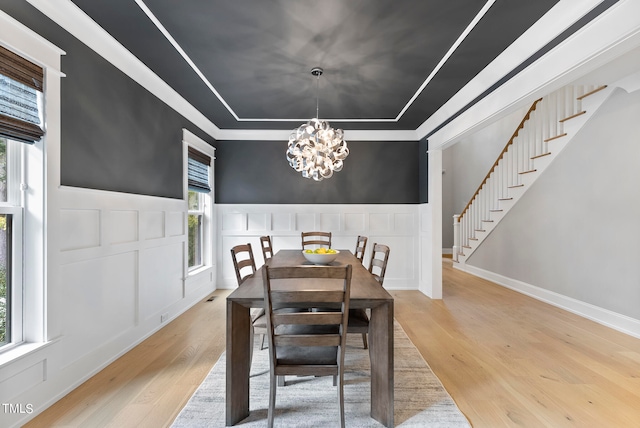 dining space with ornamental molding, a wealth of natural light, a notable chandelier, and light hardwood / wood-style floors