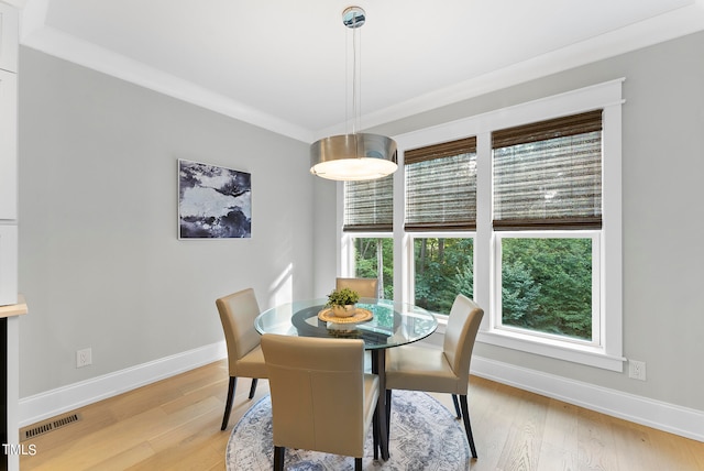 dining area with crown molding and light hardwood / wood-style flooring