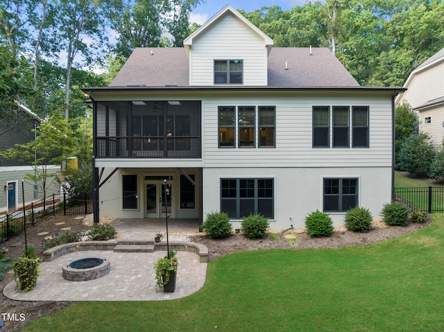 back of property featuring a fire pit, a lawn, a patio, and a sunroom