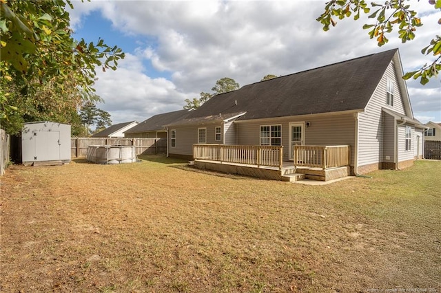 rear view of property with a yard, a storage unit, and a pool side deck