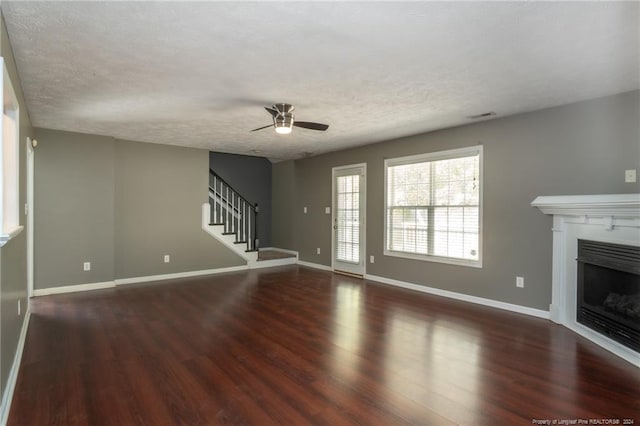 unfurnished living room featuring dark wood-type flooring, a textured ceiling, and ceiling fan