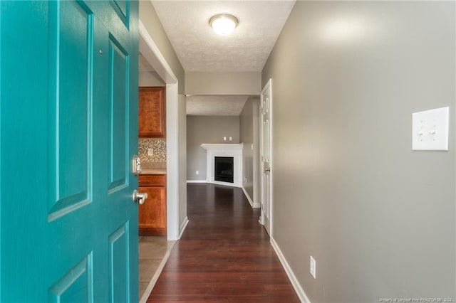 hall with dark wood-type flooring and a textured ceiling