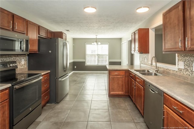 kitchen with sink, appliances with stainless steel finishes, backsplash, hanging light fixtures, and a chandelier