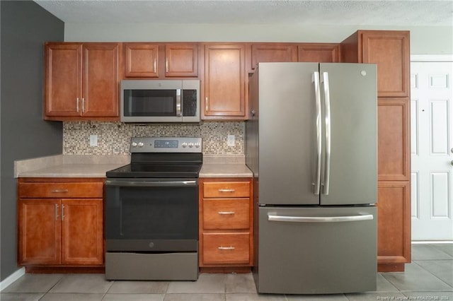 kitchen featuring stainless steel appliances, light tile patterned floors, and tasteful backsplash