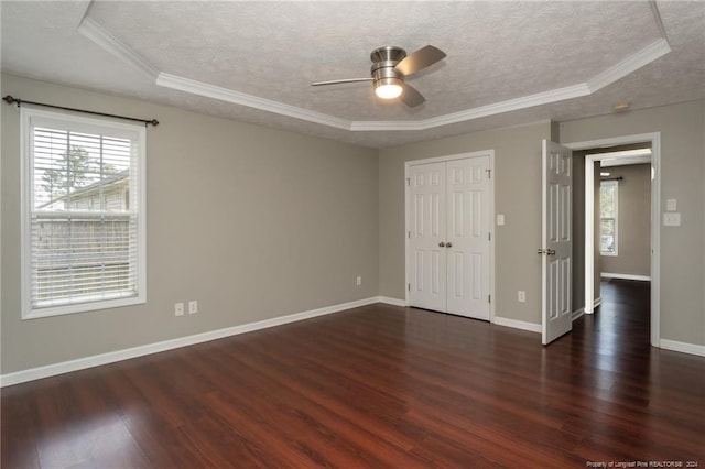 unfurnished room with ornamental molding, ceiling fan, dark hardwood / wood-style floors, a textured ceiling, and a tray ceiling