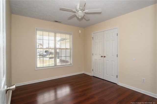 unfurnished bedroom with a textured ceiling, dark hardwood / wood-style floors, ceiling fan, and a closet