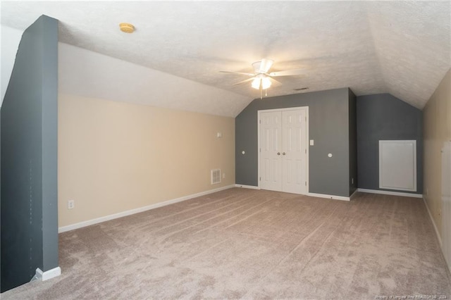 additional living space with a textured ceiling, light carpet, and vaulted ceiling