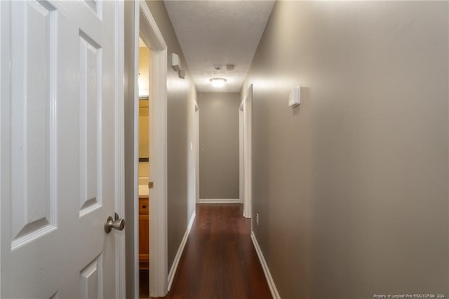 corridor featuring dark hardwood / wood-style flooring and a textured ceiling