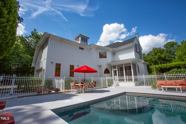 back of property with a patio and a fenced in pool