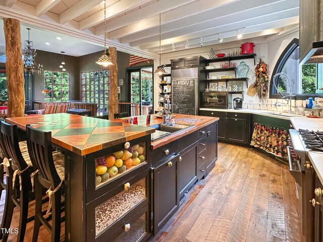 bar featuring rail lighting, sink, light hardwood / wood-style flooring, beamed ceiling, and hanging light fixtures