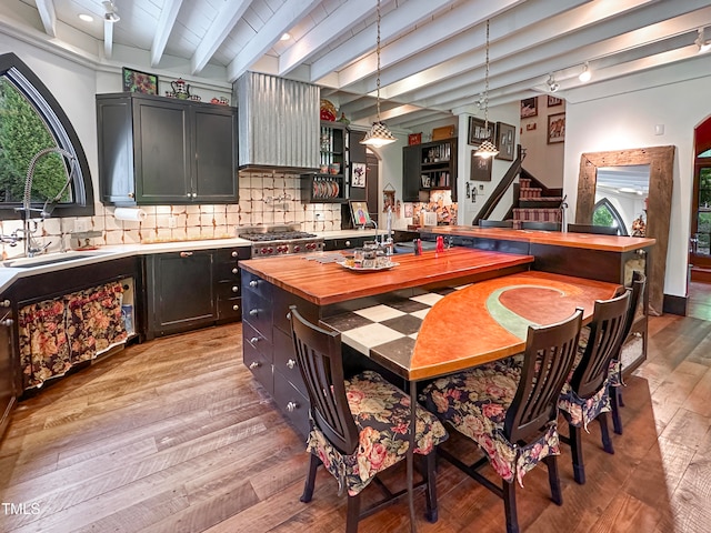 kitchen with beam ceiling, plenty of natural light, pendant lighting, and light hardwood / wood-style flooring